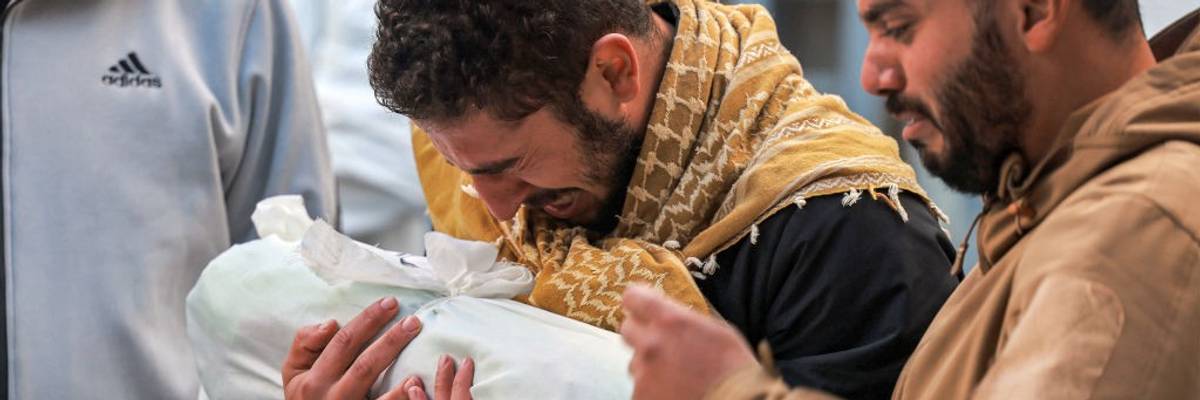 Palestinian man mourns child wrapped in cloth in Gaza on December 19, 2023