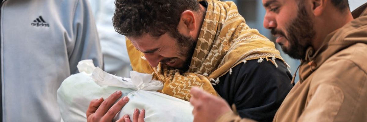 Palestinian man mourns child wrapped in cloth in Gaza on December 19, 2023