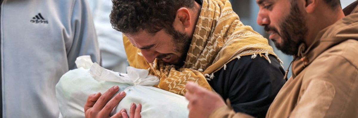 Palestinian man mourns child wrapped in cloth in Gaza on December 19, 2023