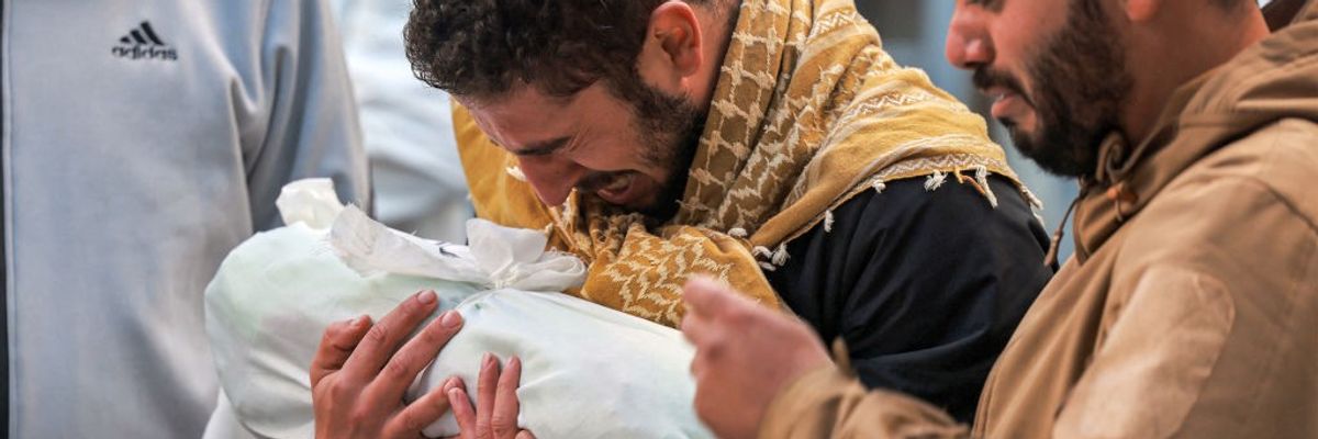 Palestinian man mourns child wrapped in cloth in Gaza on December 19, 2023.