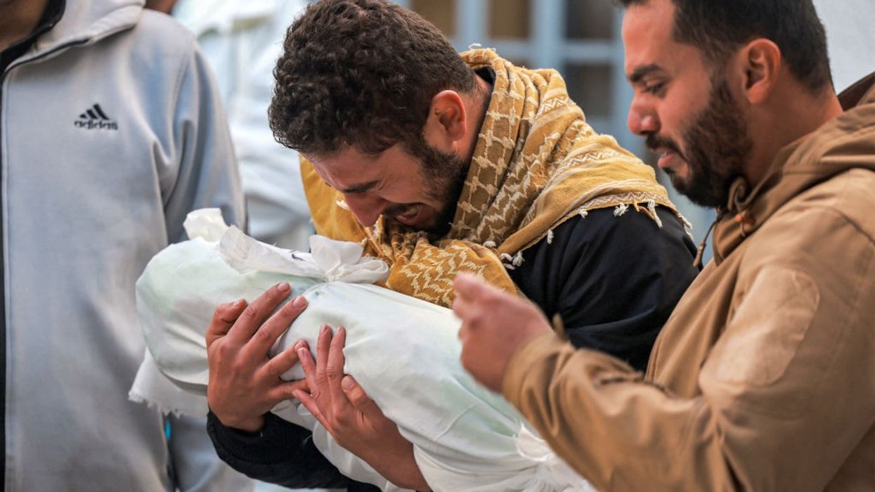 Palestinian man mourns child wrapped in cloth in Gaza on December 19, 2023