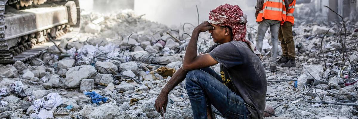 Palestinian man sits in rubble in Gaza
