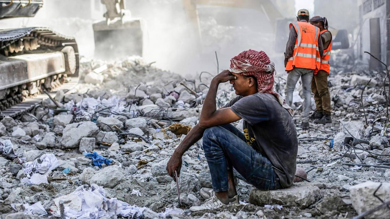 Palestinian man sits in rubble in Gaza