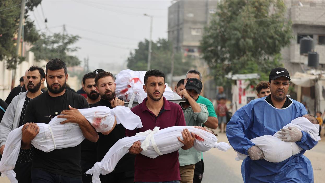 Palestinian men carry civilians—including children wrapped in white cloths—killed by Israeli attacks on Gaza.