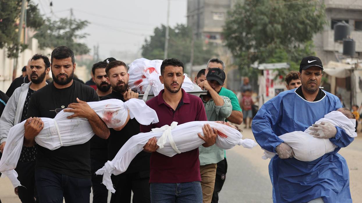 Palestinian men carry civilians—including children wrapped in white cloths—killed by Israeli attacks on Gaza.