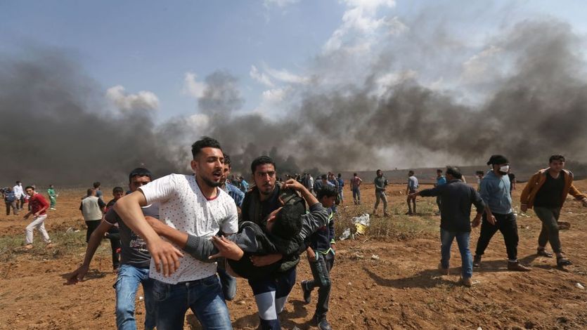 Palestinian men carry wounded comrade during Great March of Return
