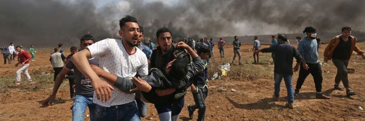Palestinian men carry wounded comrade during Great March of Return