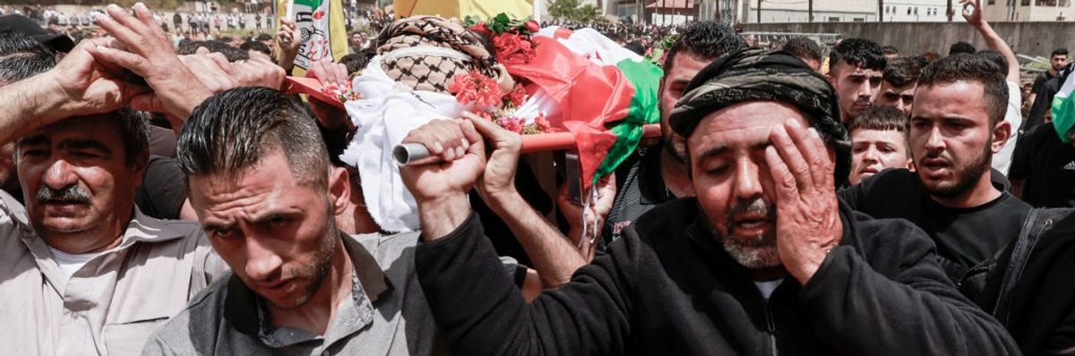 Palestinian mourners carry the bodies of men killed by Israeli settlers in the West Bank