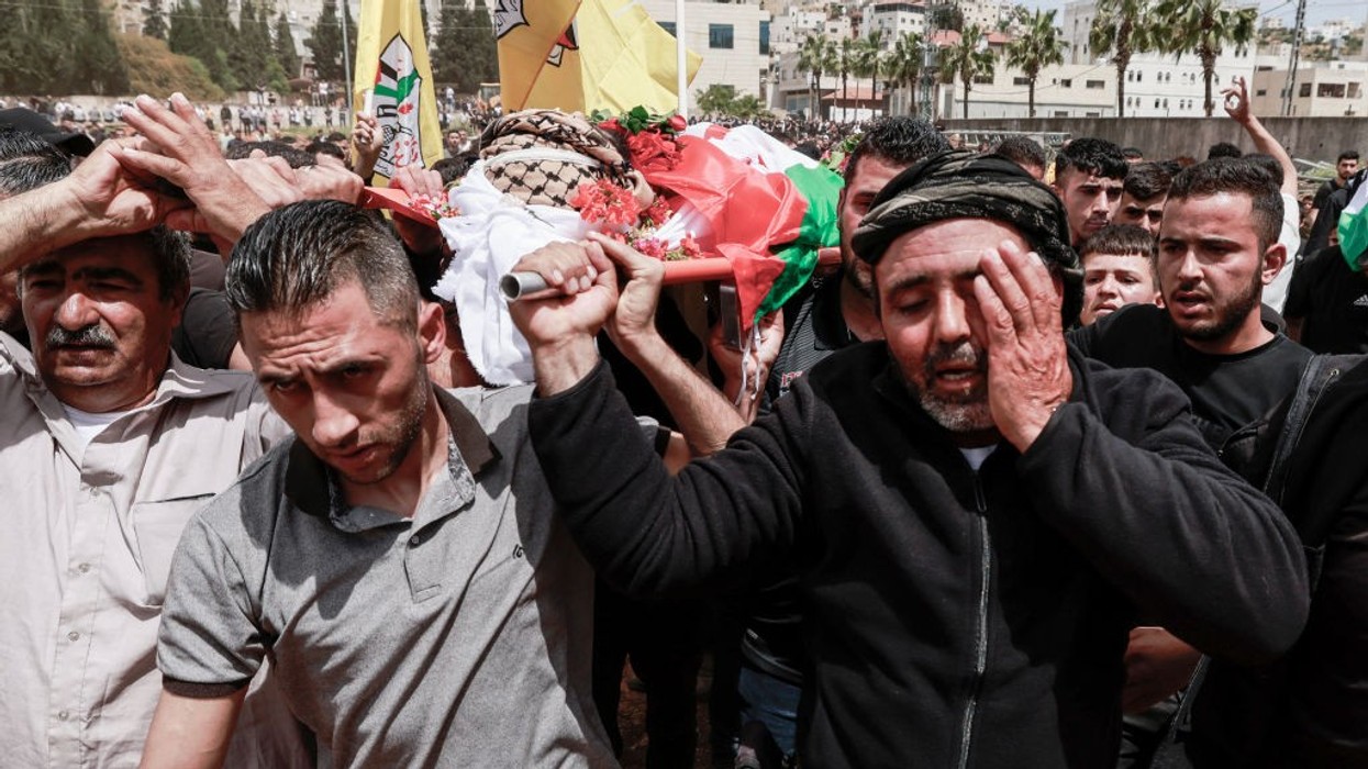 Palestinian mourners carry the bodies of men killed by Israeli settlers in the West Bank
