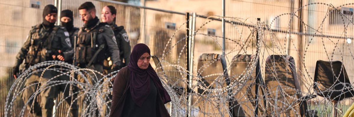 Palestinian woman in occupied West Bank, razor wires and IDF soldiers in background