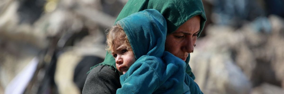 Palestinian woman with young child in her arms in Gaza.