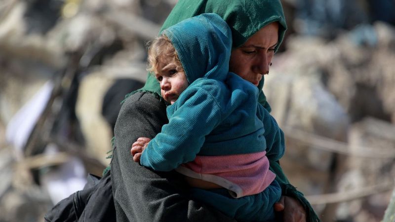 Palestinian woman with young child in her arms in Gaza.
