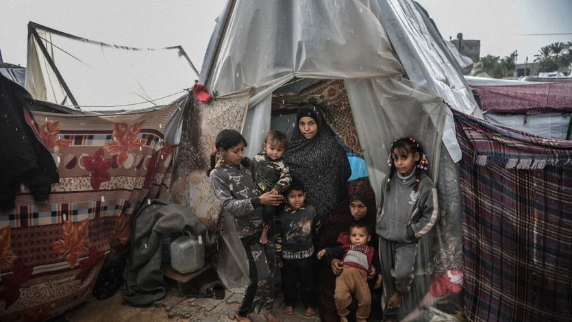 Palestinian women and children under a plastic tent as refugees in Rafah