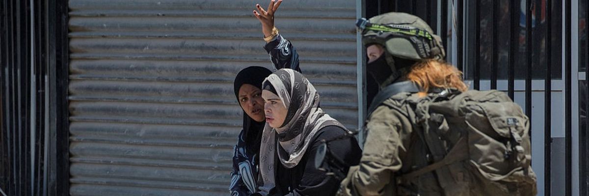 Palestinian women look at the ruins of what used to be their home
