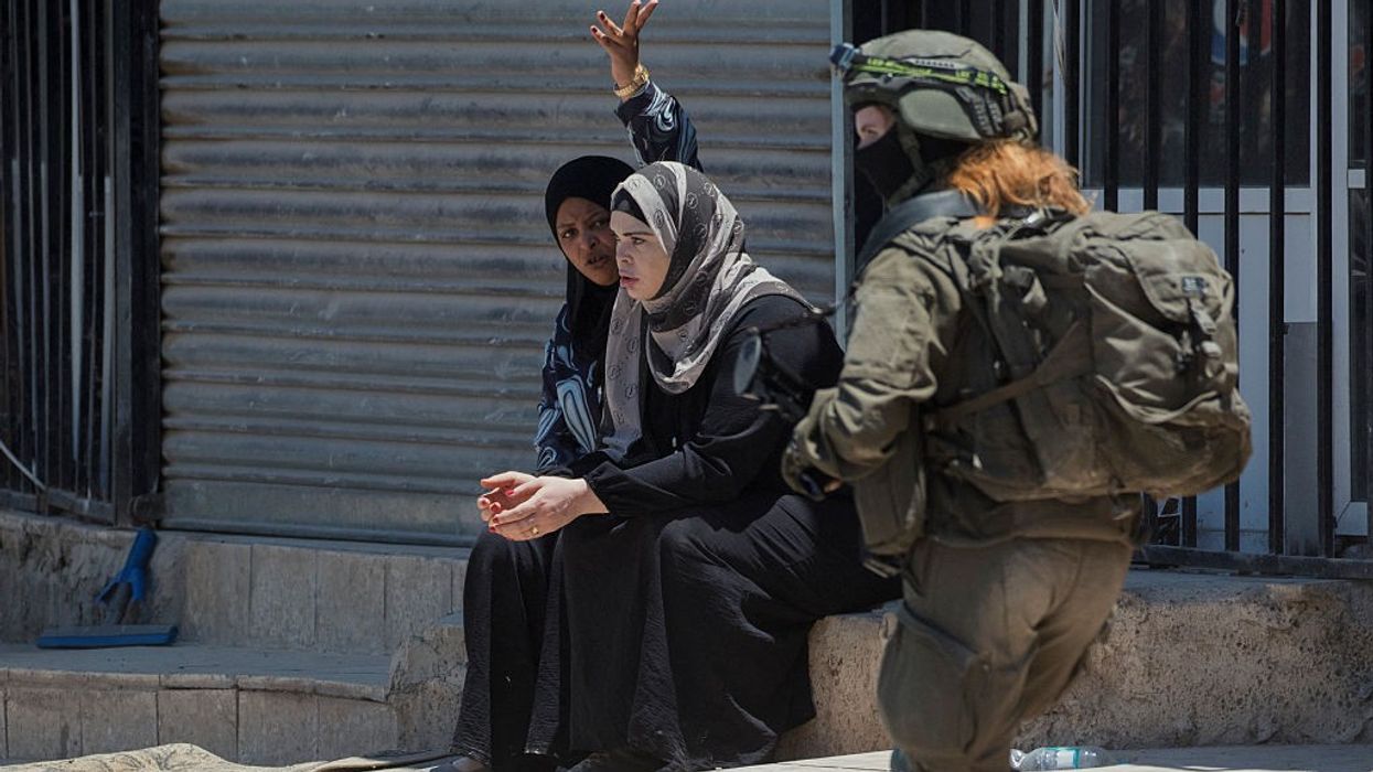 Palestinian women look at the ruins of what used to be their home