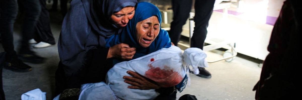 Palestinian women weep as one holds the shrouded body of a child killed by an Israeli strike