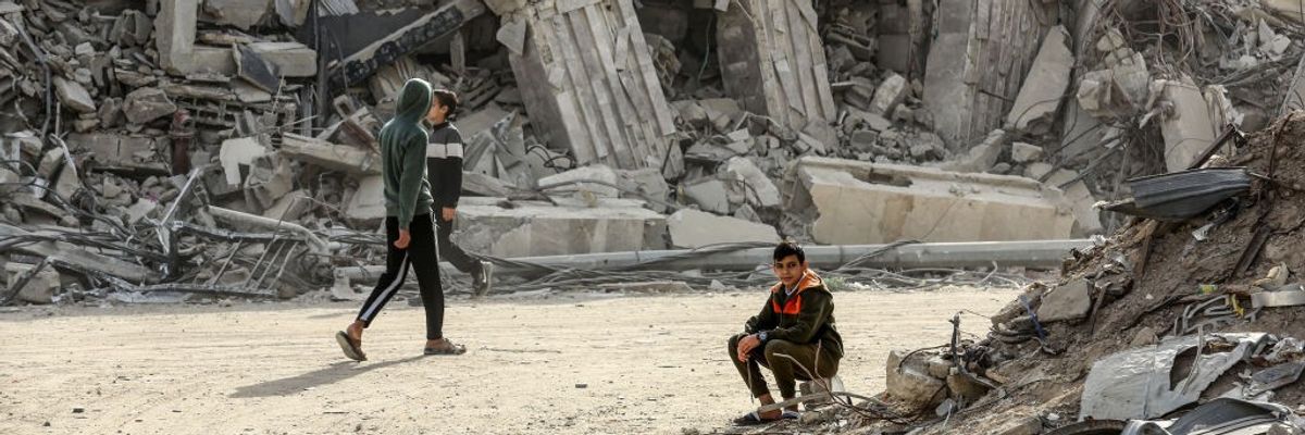 Palestinians are surrounded by buildings destroyed by Israeli attacks in Khan Younis