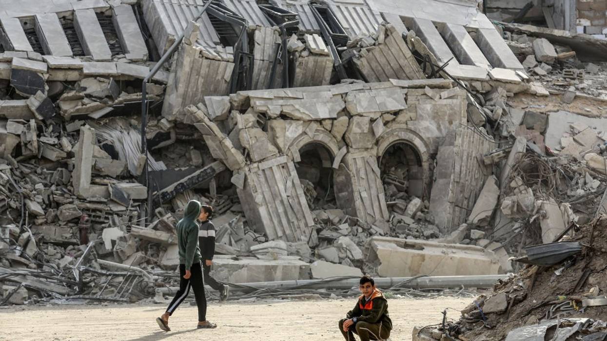 Palestinians are surrounded by buildings destroyed by Israeli attacks in Khan Younis