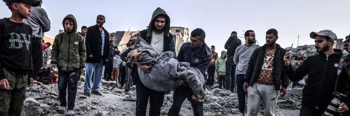 Palestinians carry a body pulled from the rubble
