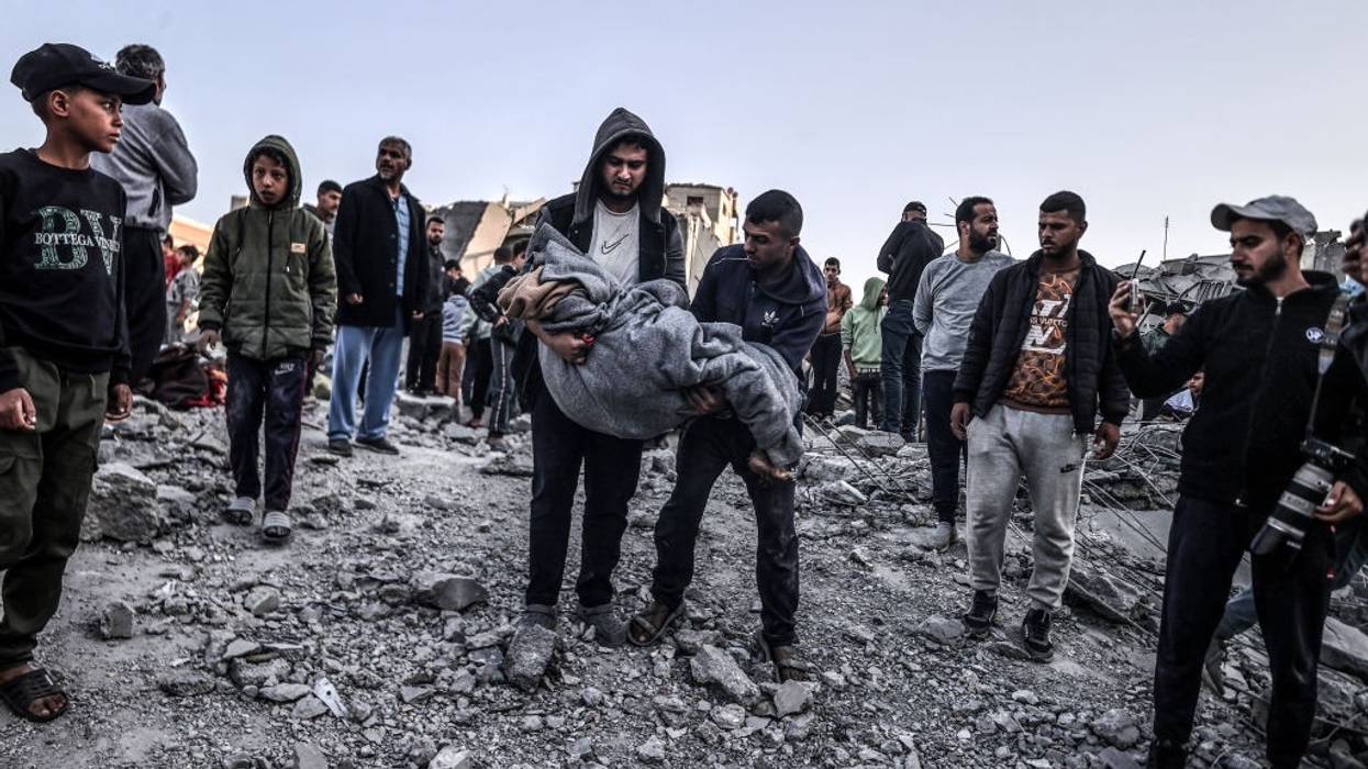 Palestinians carry a body pulled from the rubble