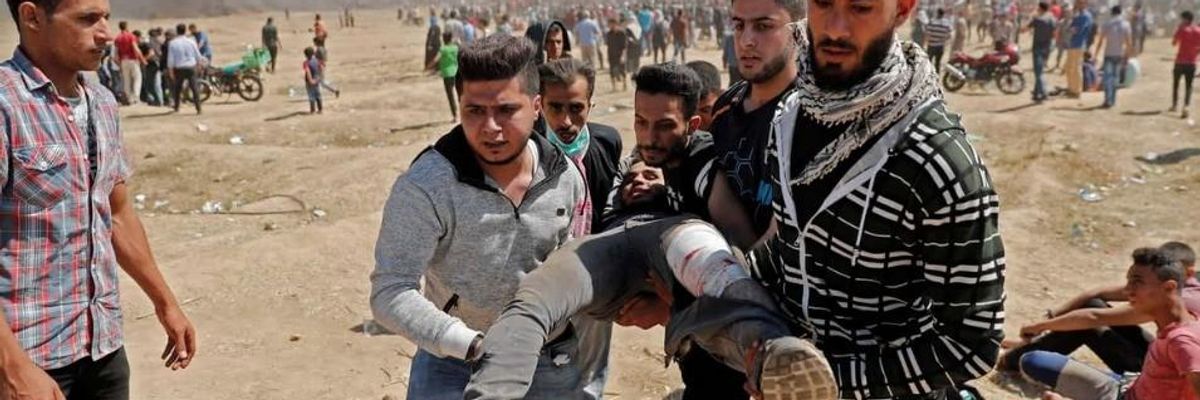 Palestinians carry injured man to safety during protests in Gaza