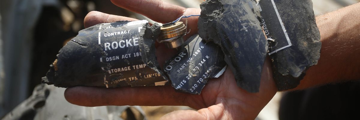 Palestinians examine shrapnel from the rocket allegedly used by Israel