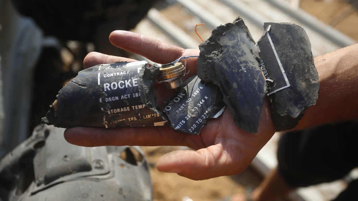 Palestinians examine shrapnel from the rocket allegedly used by Israel