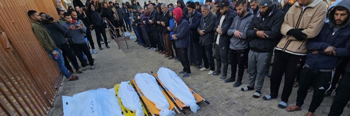 Palestinians gather around the shrouded bodies of people killed by an IDF strike