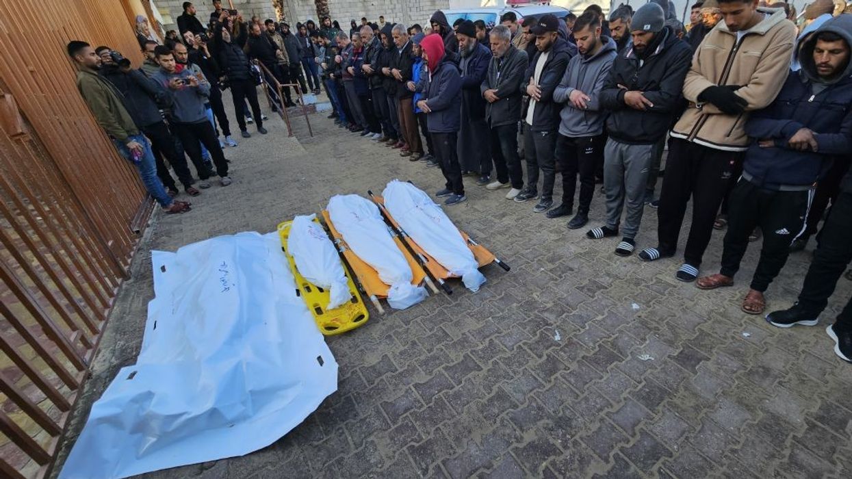 Palestinians gather around the shrouded bodies of people killed by an IDF strike