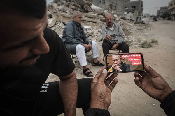 Palestinians follow coverage of the Israeli general elections on their mobile phones in the bombed-out ruins of the Gaza Strip on October 27, 2026