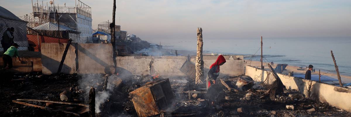 Palestinians inspect rubble by beach in Gaza.