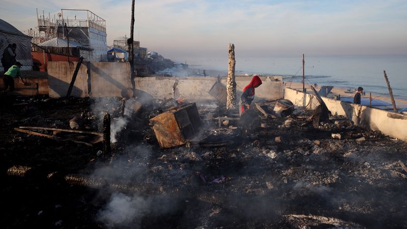 Palestinians inspect rubble by beach in Gaza.