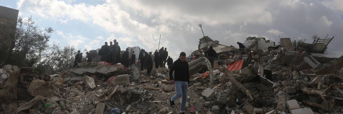 Palestinians inspect the rubble of a house
