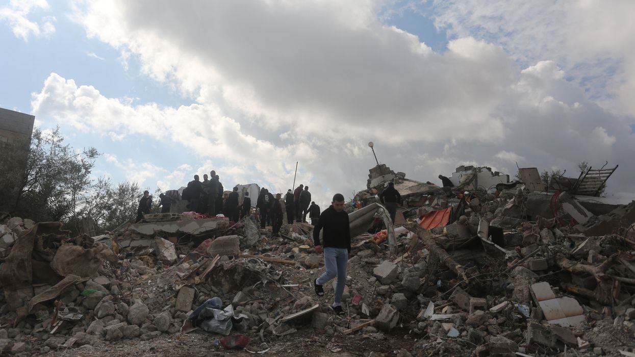 Palestinians inspect the rubble of a house