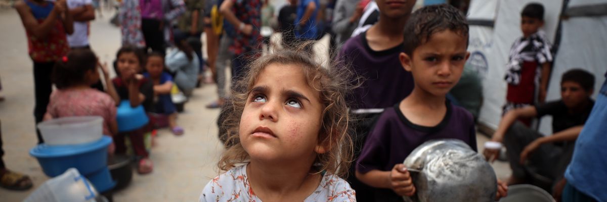 Palestinians line up to receive a hot meal at a food distribution point