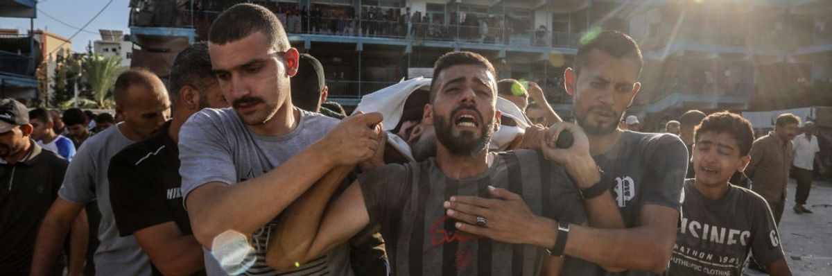 Palestinians mourn and carry the body of an UNRWA worker killed in an Israeli strike on a Gaza school