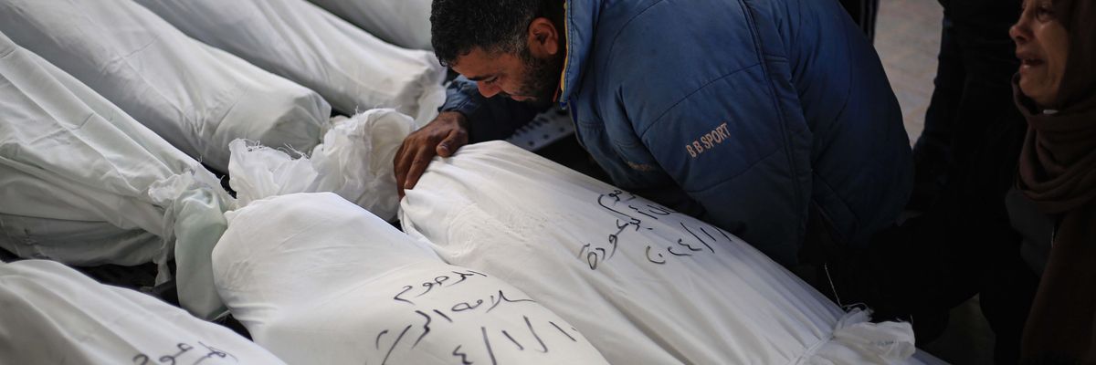 Palestinians mourn next to the bodies of their relatives