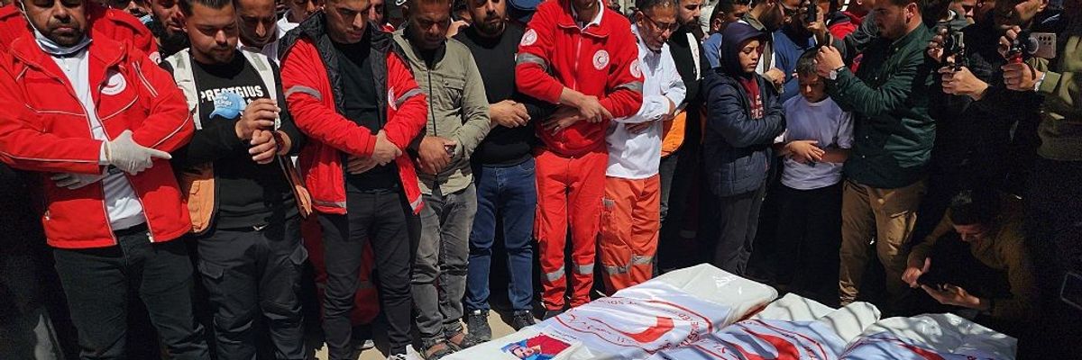 Palestinians mourn over the shrouded bodies of 8 Red Crescent workers killed by Israel