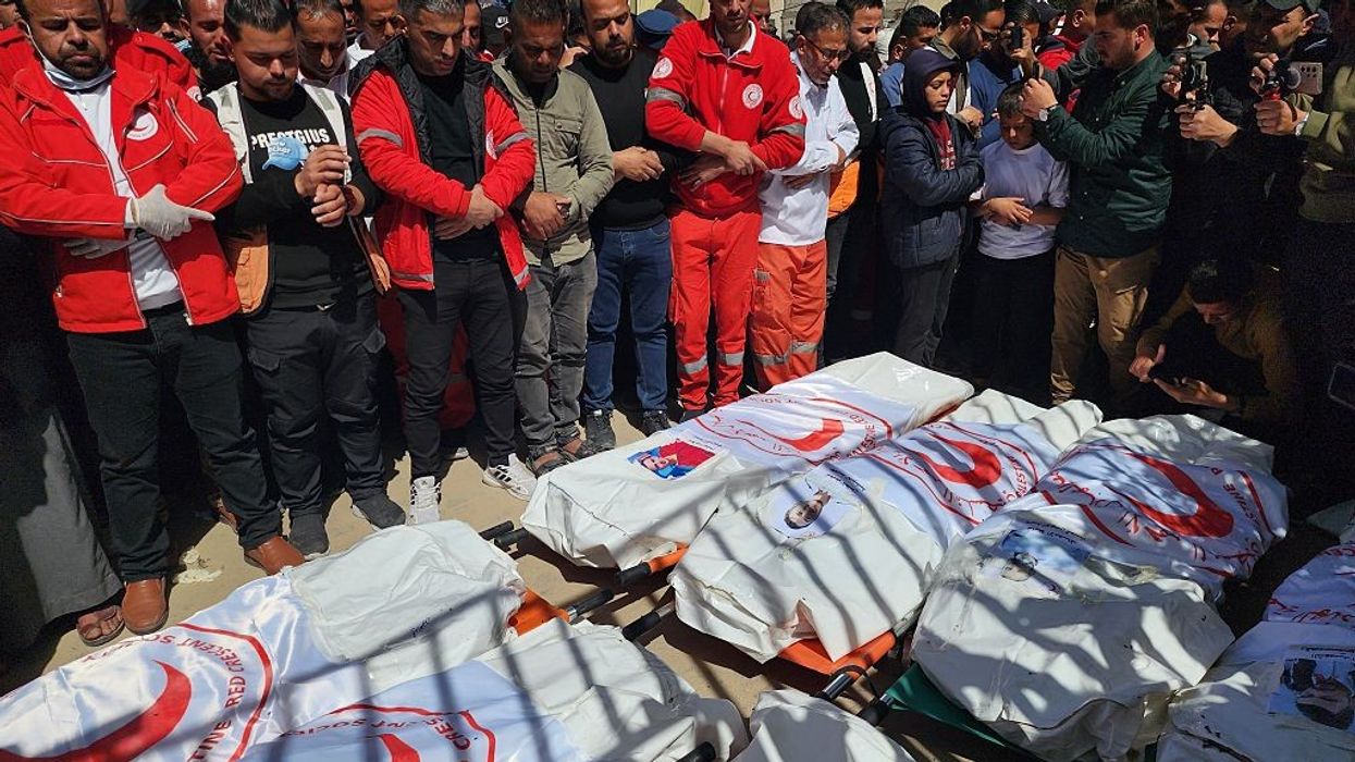 Palestinians mourn over the shrouded bodies of 8 Red Crescent workers killed by Israel