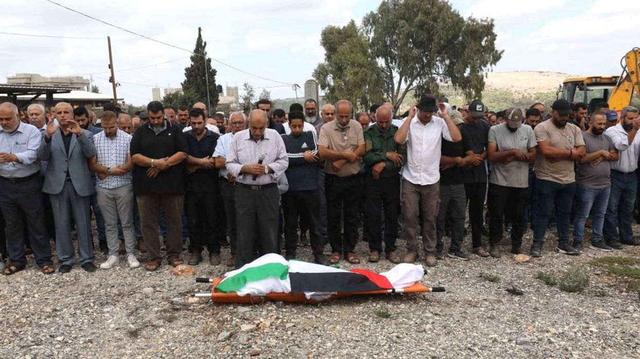 Palestinians pray over the the body of Hanan Abu Salameh, which is lying on the ground shrouded in a Palestinian flag