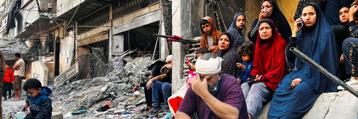 Palestinians sit amid the ruins of a building destroyed by an Israeli airstrike in Beit Lahia