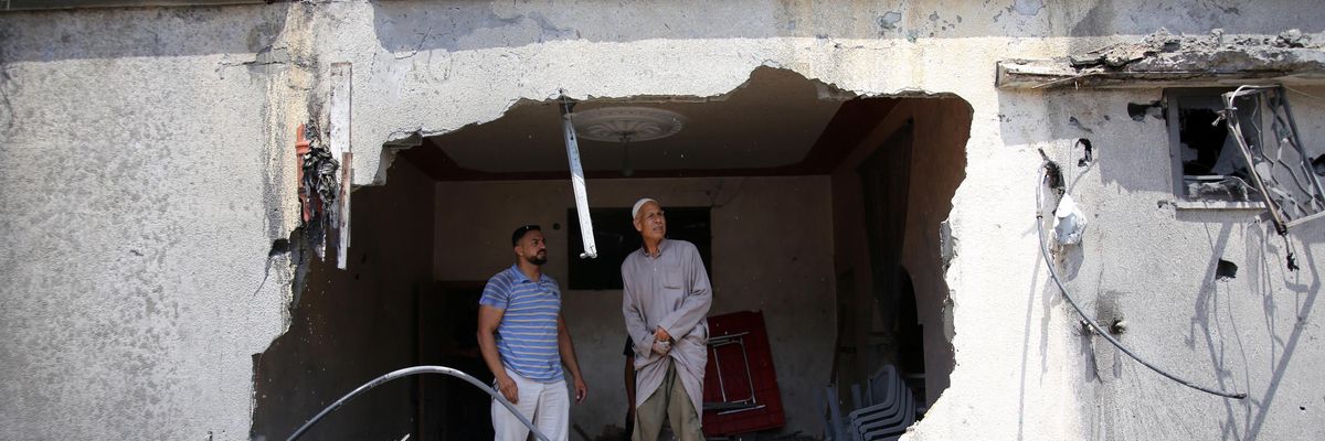 Palestinians stand in ruins of building