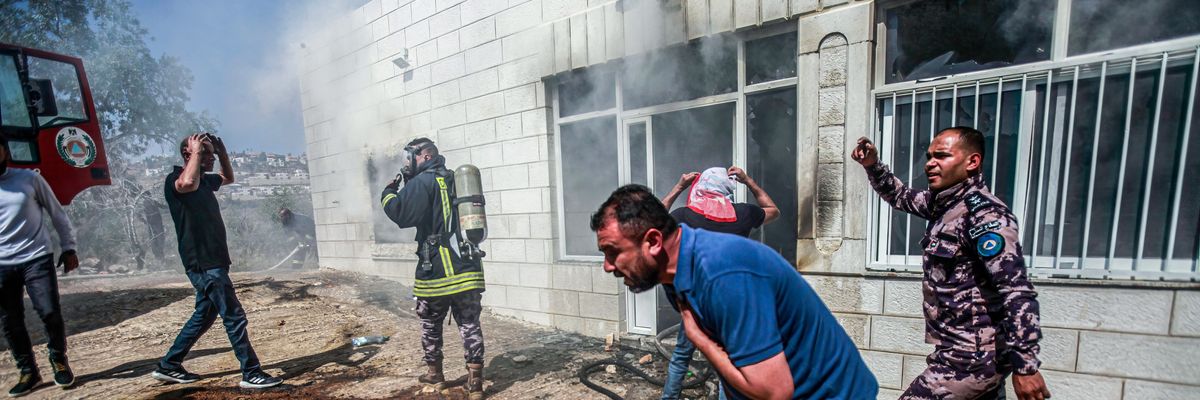 Palestinians try to extinguish a house set on fire by Israeli settlers in the town of Turmusaya