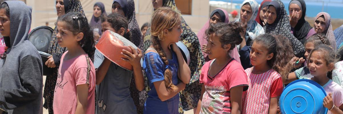 Palestinians wait in line to receive food