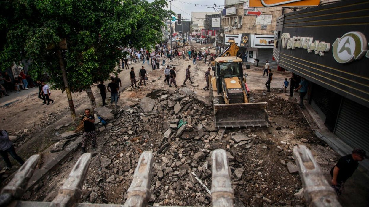 Palestinians walk around the damaged infrastructure in Jenin