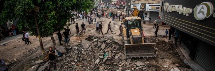 Palestinians walk around the damaged infrastructure in Jenin
