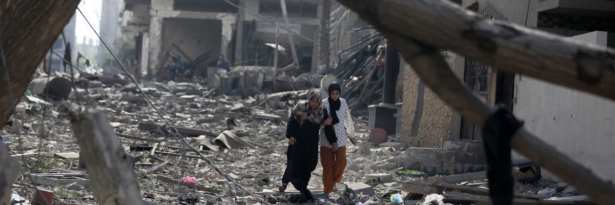 Palestinians walk through debris along a street in the aftermath of Israeli bombardment