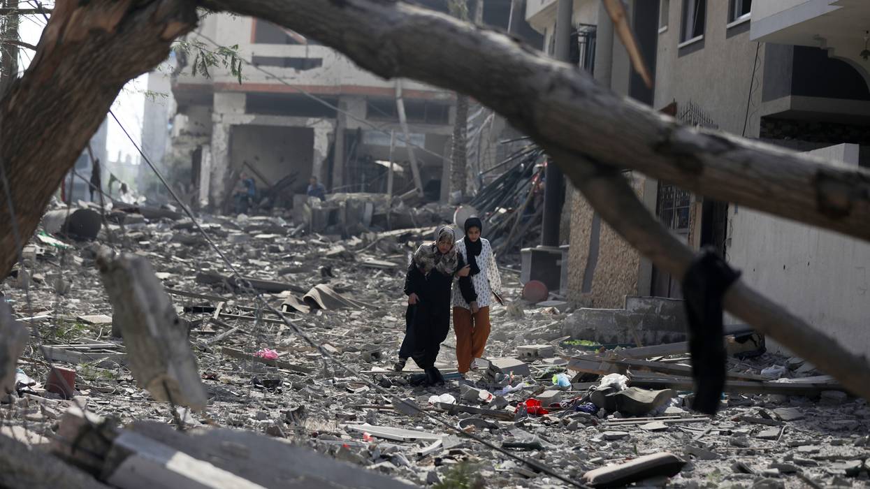 Palestinians walk through debris along a street in the aftermath of Israeli bombardment
