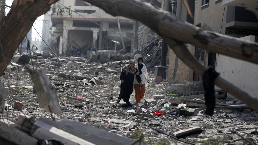 Palestinians walk through debris in Gaza