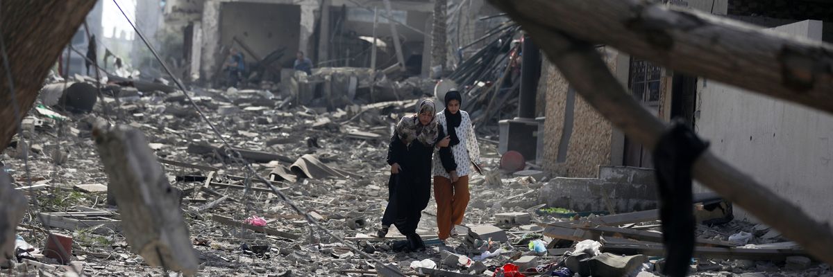 Palestinians walk through debris in Gaza